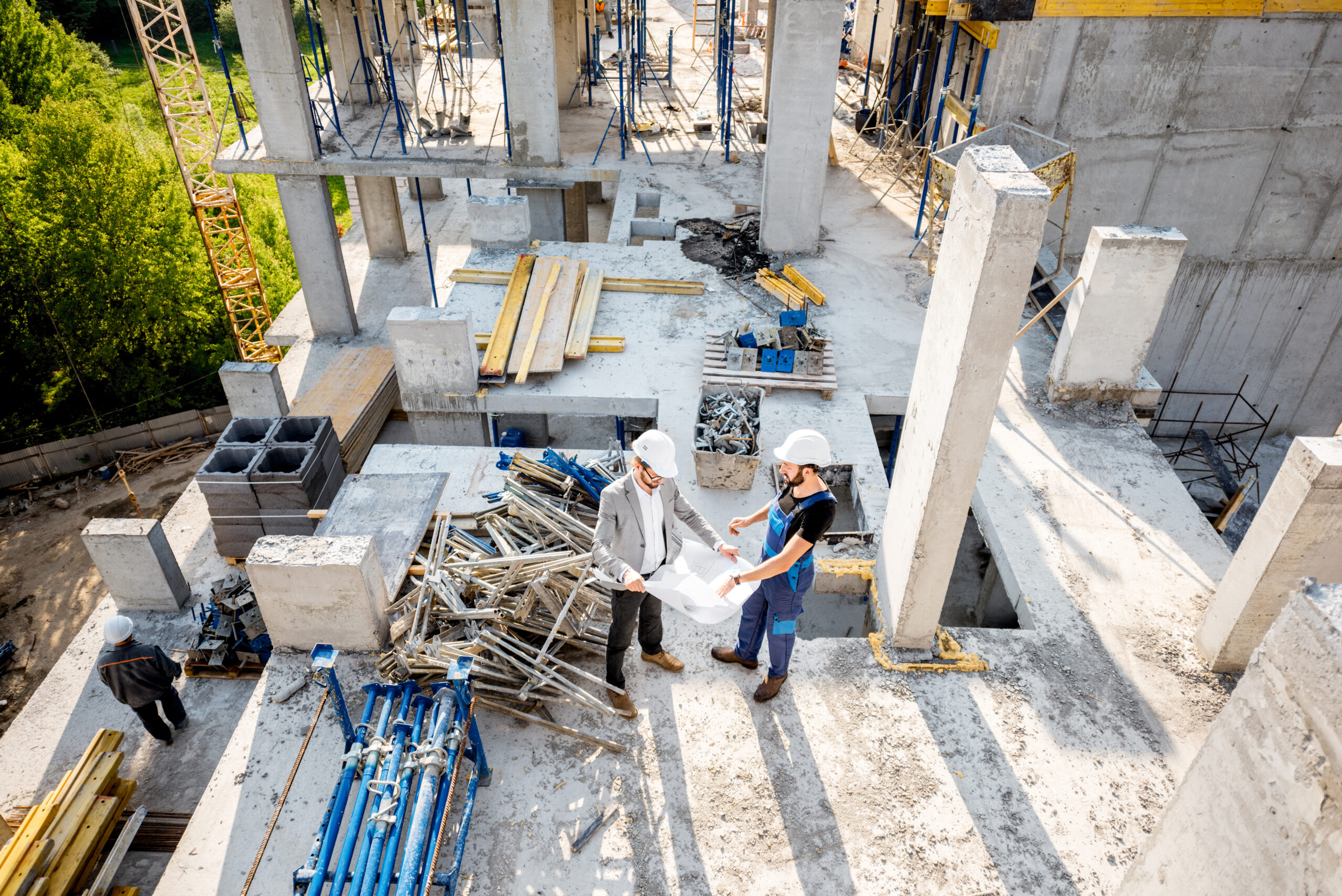 Top view on the construction site of residential buildings during the construction process with two workers standing with drawings